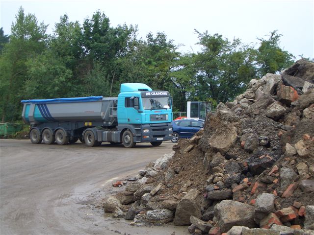 LKW steht vor einem Berg von Bauschutt. 